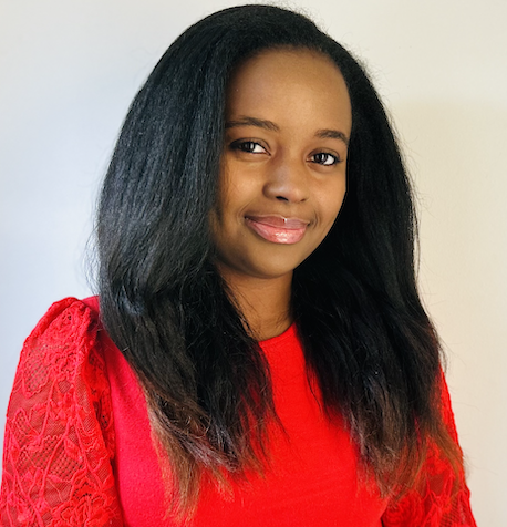 A woman with long, straight black hair wearing a red top with lace sleeves, smiling softly against a plain background.
